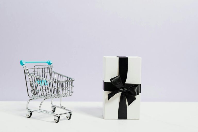 Minimalist shopping concept with cart and gift box tied with black ribbon.